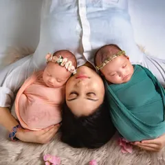 A creative overhead shot capturing a mother's love for her twin newborn girls. These types of poses are a beautiful way to document the unique bond with multiples.