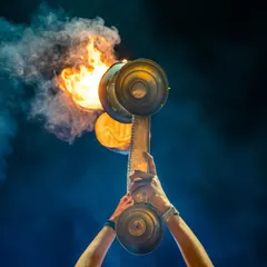 A powerful close-up of the brass fire lamps used in the Ganga Aarti. The intense flame and rising smoke against the dark sky symbolize the offering to the divine.