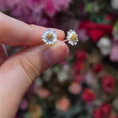 A pair of delicate daisy studs in sterling silver with gold-plated centers. A sweet and charming piece of nature-inspired jewellery.