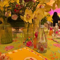 A vibrant tablescape from the Adani Mehendi, celebrating India's street food culture. The decor, with its bright yellow and floral motifs, custom water bottles, and colorful glassware, set a joyful and informal tone for the daytime celebration.