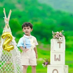 Celebrating a second birthday outdoors with a boho-themed setup, including a macrame teepee and 'TWO' blocks, set against a lush green hillside.