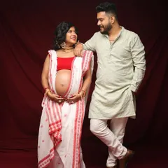 A loving couple's maternity portrait, rich with Bengali culture. The traditional saree and the couple's warm interaction create a timeless and meaningful image.