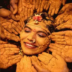 The pure joy of a Haldi ceremony. This photo captures the bride's beautiful smile as her loved ones surround her, their hands covered in turmeric, blessing her before her big day. It's a moment of tradition, love, and happiness.