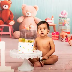 A little bit of cake on the face makes for the cutest photos. This baby is enjoying his cake smash session, surrounded by a playful teddy bear theme.