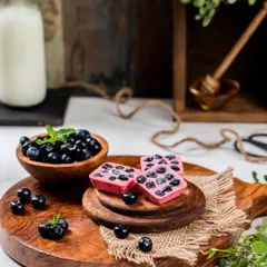 For these blueberry chocolates, I created a fresh and appealing scene with a bowl of fresh blueberries on a wooden board. The composition feels wholesome and delicious, highlighting the natural fruit ingredients.