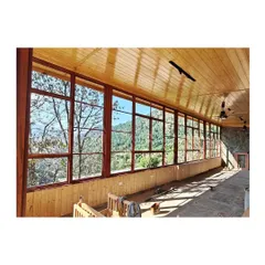 The finished interior corridor, where polished wood ceilings and a wall of windows create a warm, light-filled space. The design prioritizes the stunning views of the Kumaon hills at every turn.