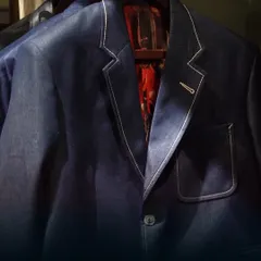 A close-up of a denim blazer, highlighting the contrast stitching and a bold, patterned lining. This piece demonstrates how we elevate a casual fabric into a sophisticated garment.