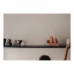 A sleek, black burnt-wood shelf is filled with curios from around the world. This guest bedroom is designed to be a place to reminisce and laze, and these personal objects, carefully arranged, add to the room's story and character.