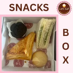A classic snack box combination with a savoury puff, a chutney sandwich, a chocolate muffin, and a cookie. It offers a balanced mix of flavours and textures.