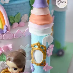 A close-up of the castle tower, showing the hand-textured brickwork and the tiny, ornate golden frames, all crafted from fondant.