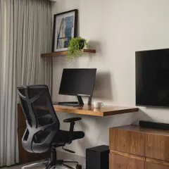 Even a small corner can become a functional workspace. Here, a simple floating wooden desk and shelf provide a dedicated spot for work without taking up much floor space. It's an efficient use of space in a multi-purpose room.
