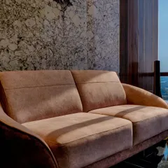 A detail of the plush seating in Mr. Siraj's cabin, set against a dramatic marble wall. The contrast between the soft fabric, the polished stone, and the warm wood creates a sense of understated grandeur.