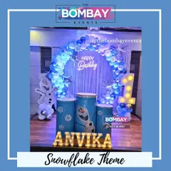 Let it go! This Snowflake and Frozen theme is perfect for a winter wonderland birthday. The setup features an icy blue and white balloon ring, Olaf cutouts, and a light-up number '1'.