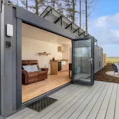 A view of our solar-powered container home, featuring a large deck and bi-fold doors that open up the living space. This design is perfect for off-grid living without sacrificing modern comforts.