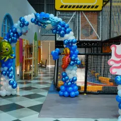 An enchanting 'Under the Sea' birthday theme, complete with blue and white balloons, shark and octopus cutouts, and seahorse details to make a magical underwater world.