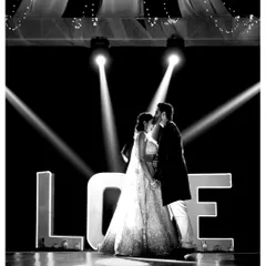 Serving main character energy. This dramatic black and white shot from a romantic beach Sangeet captures the couple in the spotlight, framed by a giant "LOVE" sign.