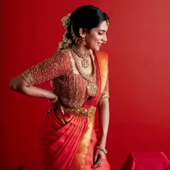 A joyful smile from the bride, capturing the emotion of her special day. The red and gold ensemble glows, highlighting the timeless beauty of traditional South Indian bridal attire.