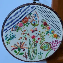 Hoop art allows me to paint with thread, creating detailed botanical scenes that can be treasured forever. This piece combines various freestyle stitches to capture the delicate forms of flowers, leaves, and a butterfly, turning a simple hoop into a captivating piece of wall decor.