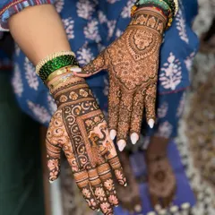 This Teej mehendi combines two different styles. One hand features a traditional peacock and floral design, while the other has a more modern, dense pattern.