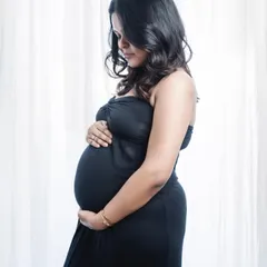 A classic maternity portrait. The simple black dress and soft backlighting create a gentle and intimate photo, highlighting the beautiful silhouette of the baby bump.