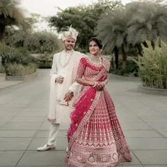 A full-length portrait showcasing the couple's magnificent wedding attire. The grandeur of the bride's lehenga and the groom's sherwani is captured perfectly.