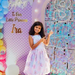 Proudly turning eight. We love capturing these milestone portraits that showcase the birthday child's personality. Here, Ira stands beside her shimmering, custom birthday backdrop, marking her special day.