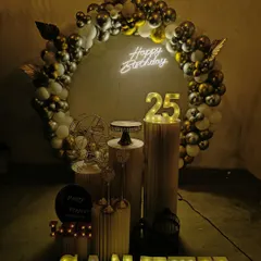 I create moody and stylish setups for milestone birthdays, like this 25th celebration. The decor uses a dark, sophisticated color scheme with a gold and black balloon arch, a neon sign, and light-up numbers and name for a cool, modern vibe.