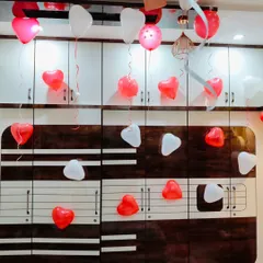 Simple and sweet romantic decor with red and white heart-shaped balloons floating on the ceiling and attached to the wall.