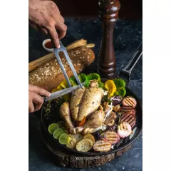A whole grilled chicken being carved, surrounded by roasted vegetables. This action-oriented shot for Double Tree by Hilton creates a sense of a generous, freshly prepared feast.