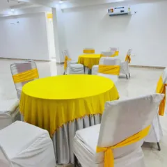 Simple and clean guest seating for a Haldi function. I provided round tables with yellow tablecloths and chairs with white covers and matching yellow sashes.