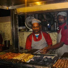 Our chefs at the grill, surrounded by skewers of chicken and mutton kebabs. This scene has been a constant at Bademiya for decades.