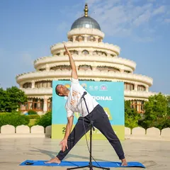 An instructor demonstrates Trikonasana (Triangle Pose) during an International Day of Yoga event. Our yoga sessions are guided by experienced teachers who ensure proper alignment and help you get the most out of each posture.