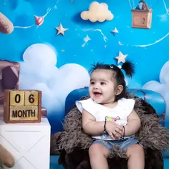 Celebrating a six-month milestone with our popular teddy bear and clouds theme. Her happy expression shows how much fun these sessions can be.