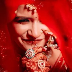 A bride's smile behind her veil is pure magic. This candid close-up captures the joy and shyness of the moment, highlighting the beautiful henna and bridal rings that complete her look.