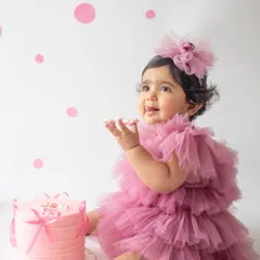 A first birthday is a huge milestone, and a cake smash is the perfect way to celebrate. This little one is having the best time with her very own pink cake in a clean, minimalist setup.