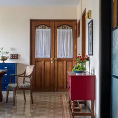 This Calcutta living room was designed to hold a family's energy and memories. We kept the soul of their old bungalow by using warm woods, patterned heritage tiles, and pops of color like this red console. The goal was to create a space that feels generous and grounded, where stories can be passed down for generations.