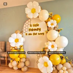 A sweet "A Little Honey is on the way" baby shower theme, with a honeycomb backdrop, daisy-shaped balloons, and a warm yellow and beige color scheme.