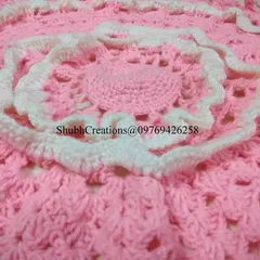 A close-up of a delicate pink and white crochet piece, perfect for a baby blanket or a decorative table mat. This design teaches you how to work in the round and create beautiful layered effects.