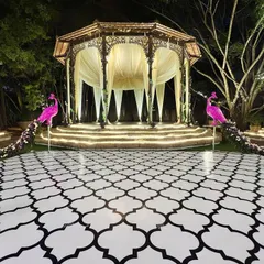 An immaculate Sangeet setup featuring a magnificent dome stage and a custom-printed dance floor. The two tall, shining pink peacock installations were the stars of the evening.
