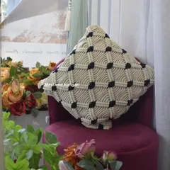 Our black and white macramé cushion cover, styled on a plush chair. The geometric pattern adds a modern yet cozy touch to any living space.