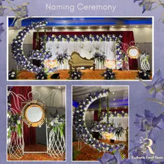 A complete naming ceremony setup featuring a modern floral moon cradle. The stage includes a backdrop of white drapes and a creative stand for the name reveal mirror, all tied together with elegant purple and white floral arrangements.