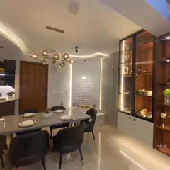 A closer look at the dining area, featuring a modern 6-seater table and a stylish glass-and-wood crockery unit with internal lighting to display decorative items.