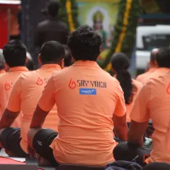 A view from behind of our students during a seated meditation at the International Yoga Day event. The matching orange shirts with the SAY Yoga logo reinforce our identity as a unified tribe.