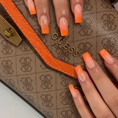 A bold and fiery sunset ombré with long, square-shaped extensions. The vibrant orange fades into a soft nude base, with a touch of gold glitter for extra flair.