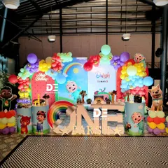A cheerful Cocomelon first birthday for Darsh. This party features a rainbow balloon arch, multiple character cutouts, and a large 'ONE' table, creating a perfect setting for a memorable celebration.