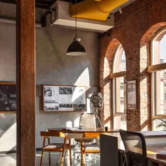 The beginning of The Loft's story. This is our main studio space, where sunlight floods in through the restored arched windows, illuminating the exposed brick and concrete walls. It's a space designed to inspire creativity and collaboration.