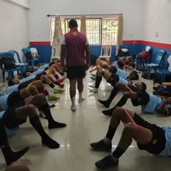 A coach oversees a pre-match activation session. Our players are performing glute bridges with resistance bands, a key exercise for core stability and injury prevention.