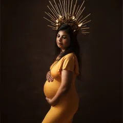 Motherhood is a royal affair. This portrait, with its golden gown and majestic crown, celebrates the queen that every mother-to-be is. It's a statement of strength, grace, and the miracle of creation.
