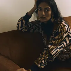 An intimate and relaxed moment captured on the couch. The soft, warm lighting creates a cozy atmosphere, while the model's gaze draws the viewer into the scene.
