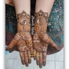 A beautiful design for the bride's mom, featuring peacock and lotus mandalas on the back of the hands, surrounded by floral details.